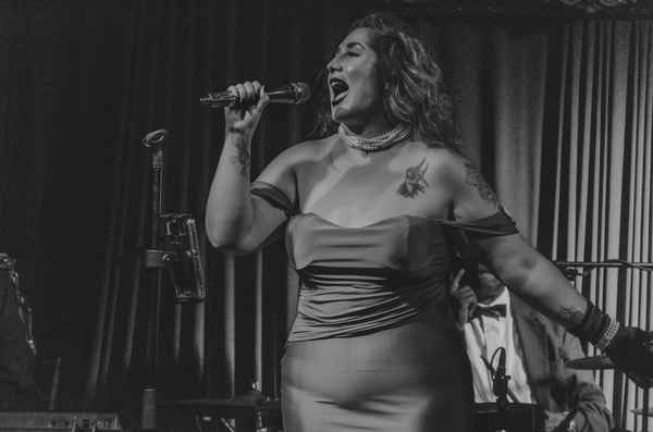 Professional picture of one of our Spanish cover singers for events passionately belting into microphone while at private onstage event | Altus Entertainment